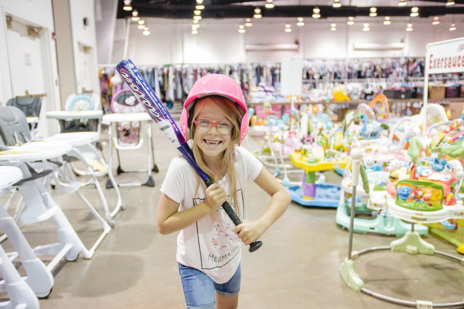 Three young girls are excited to shop together in the toy section of their local JBF sale.